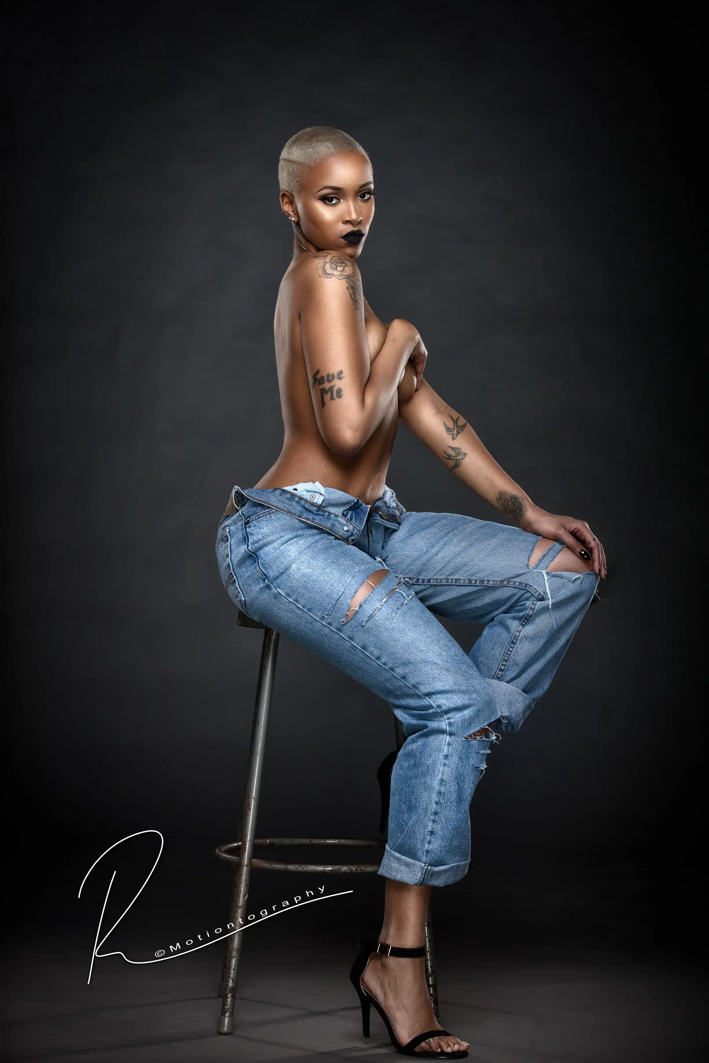 Empowering boudoir photo of woman in ripped jeans