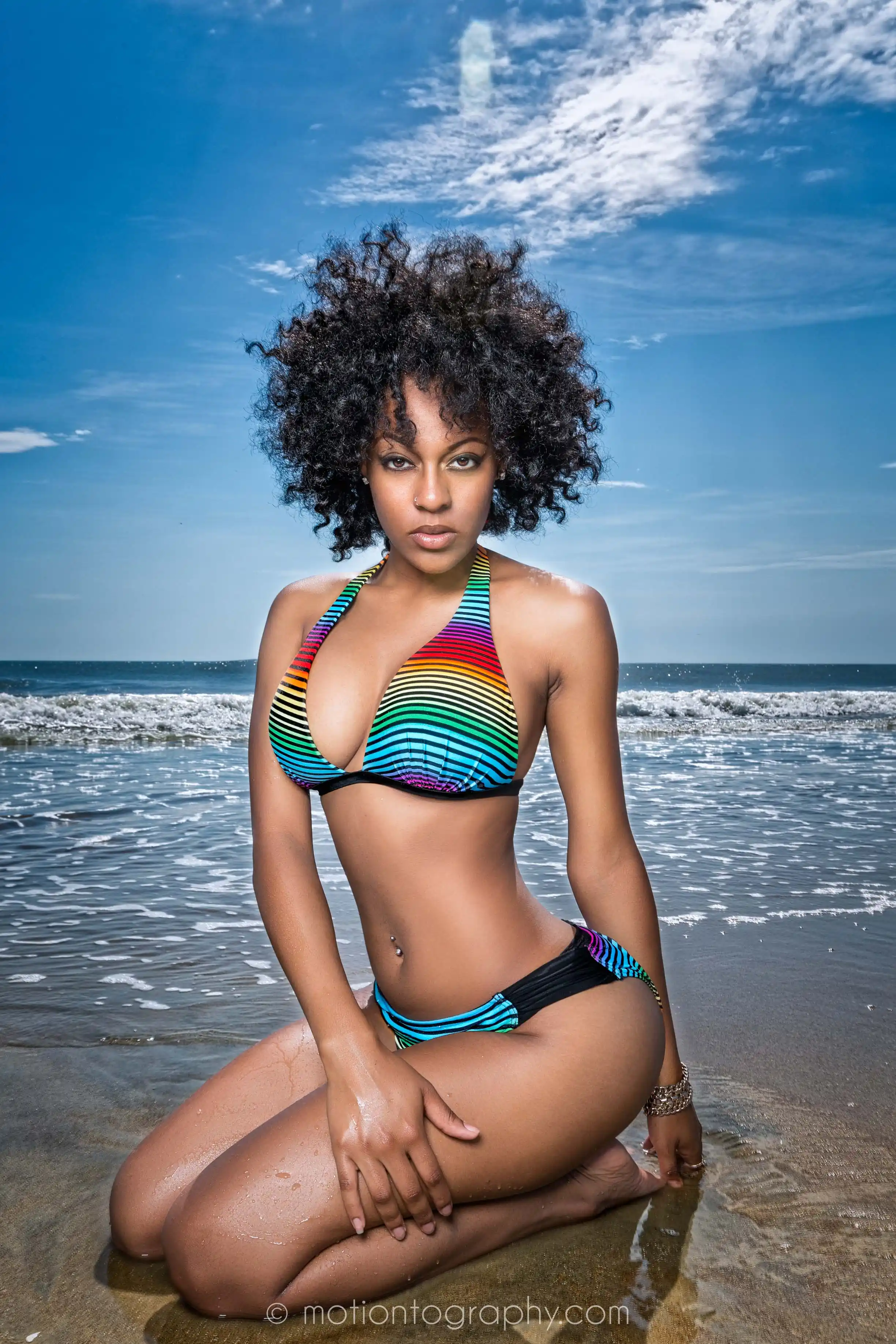 On location beach photo woman kneeling rainbow bikini